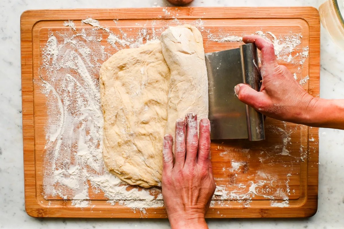 Bench Scraper: metal bench scraper being used with bread dough