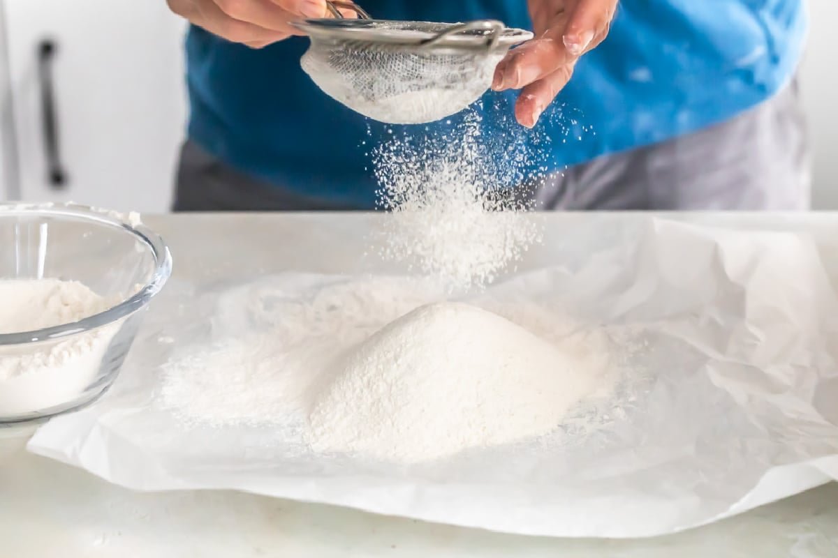 Bolting: hands sifting fresh-milled flour through a sieve